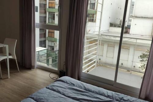 1 dormitorio con cama y ventana grande en Luminoso Monoambiente con Balcón al Frente Ciudad de la Paz y Rivera en Buenos Aires