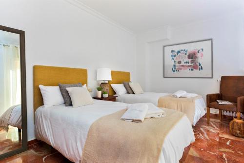 Habitación blanca con 2 camas y espejo. en Genteel Home Ático Gran Capitán, en Granada