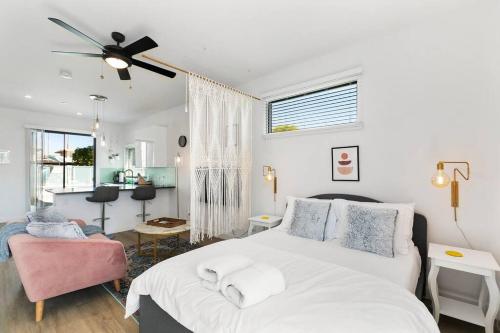 a bedroom with a white bed and a pink chair at Large Studio Rooftop & Poolside - Walk to Old Town in Scottsdale
