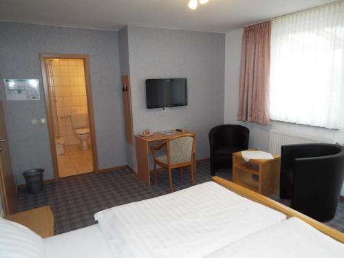 a hotel room with a bed and a desk and a television at Hotel garni Zum Reinhardswald in Gewissenruh