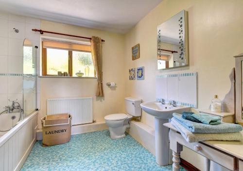 a bathroom with a sink and a toilet and a tub at Maes Mihangel in Llanfihangel-y-Pennant