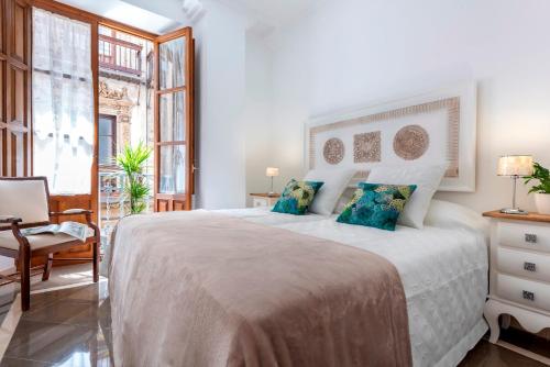 1 dormitorio blanco con 1 cama grande con almohadas azules en Genteel Home Sagrado Corazón, en Granada