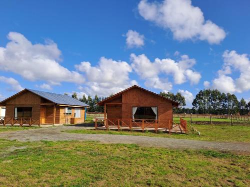 two wooden buildings in a field with a sky at Cabañas Kaykun in Puerto Octay