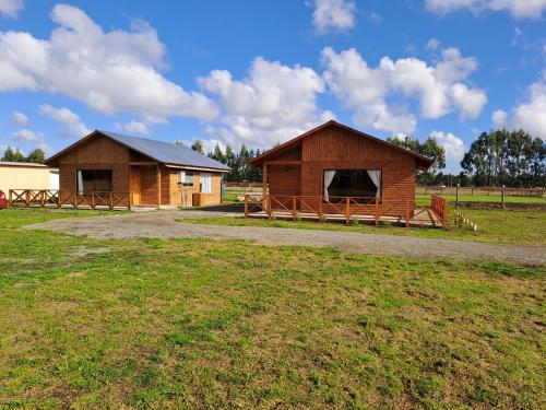 two buildings in a field next to a grass field at Cabañas Kaykun in Puerto Octay