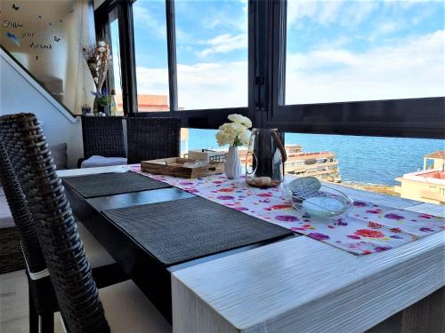 a dining room table with a view of the ocean at Cabo Cervera primera linea apartamento de lujo in Torrevieja