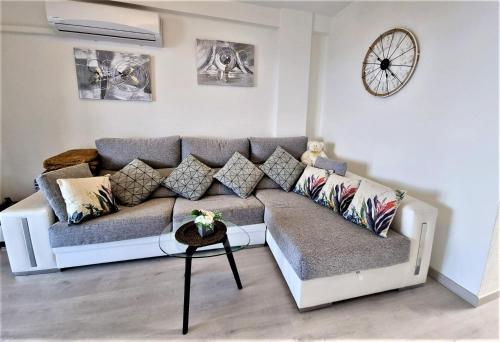 a living room with a couch and a clock on the wall at Cabo Cervera primera linea apartamento de lujo in Torrevieja