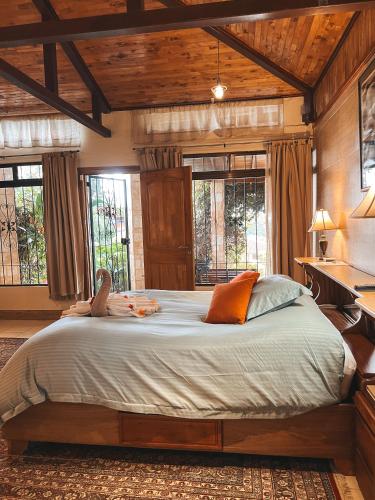 a bedroom with a large bed in a room with windows at Finca Paraiso Mountain Retreat near San Jose Airport in Birrí