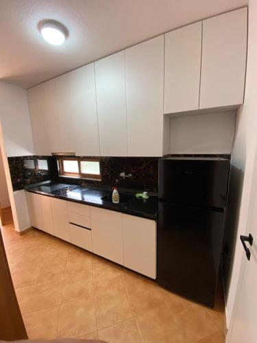 una cucina con frigorifero nero e armadietti bianchi di Hotel Garden Villa ARDO a Golem