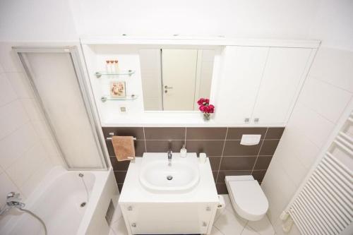 ein Badezimmer mit einem Waschbecken, einem WC und einem Spiegel in der Unterkunft Apartment Zara White in Zadar