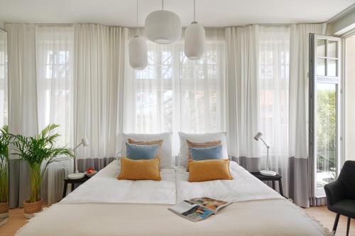 sypialnia z dużym łóżkiem z poduszkami i oknami w obiekcie Sanhaus Apartments - Apartamenty Oslo z klimatyzacją w mieście Sopot