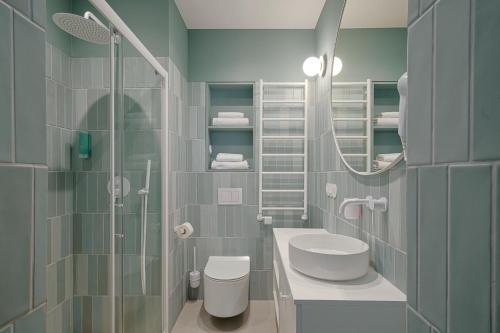 een badkamer met een douche, een wastafel en een spiegel bij Sanhaus Apartments - Apartamenty Oslo z klimatyzacją in Sopot