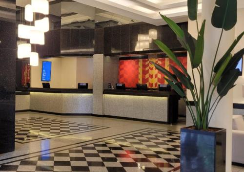 a lobby with a checkered floor and a potted plant at Manhattan Plaza in Brasília