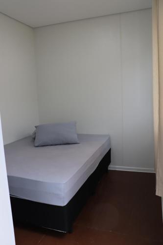 una cama en una habitación con una pared blanca en Canela Container, en Canela