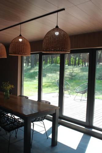 een eetkamer met een tafel, stoelen en ramen bij Villa Forest in Dumantsy