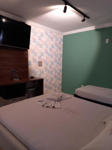 a room with two beds and a desk and a television at Hotel 1001 Prime Ade Águas Claras in Águas Claras