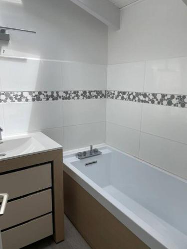 une salle de bain avec un lavabo, une baignoire et un comptoir dans l'établissement Maison de charme à la Couarde-sur-Mer, à La Couarde-sur-Mer