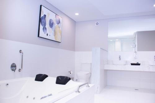a white bathroom with a sink and a toilet at Bisinii Boutique Hotel in Ciudad del Este