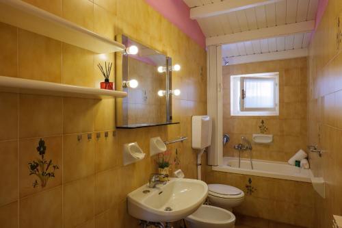 ein Badezimmer mit einem Waschbecken, einem WC und einem Spiegel in der Unterkunft Casa del Sole in Colico
