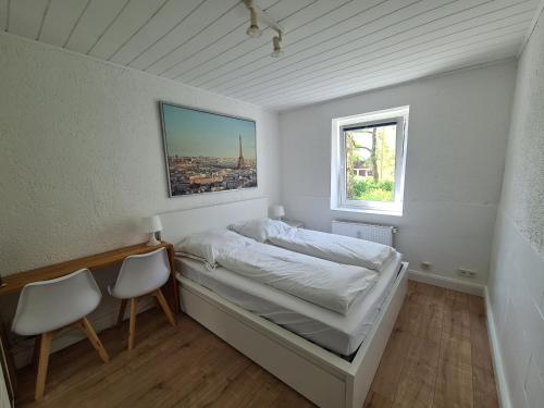 een slaapkamer met een bed met 2 stoelen en een raam bij Ruhige Ferienwohnung an der Messe in Hannover