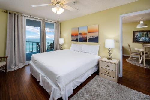 um quarto com uma grande cama branca e uma varanda em Nautilus 1603 - Gulf Front 2 Bedroom - 6th Floor em Fort Walton Beach