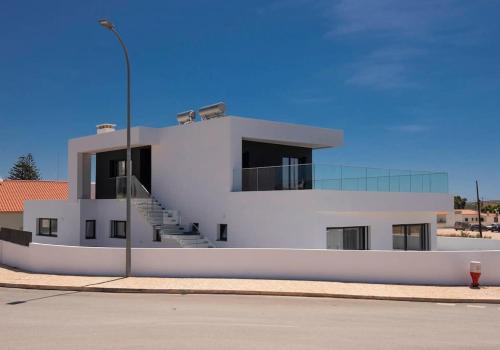 a white building with stairs and a street light at Sunset House in Vila do Bispo