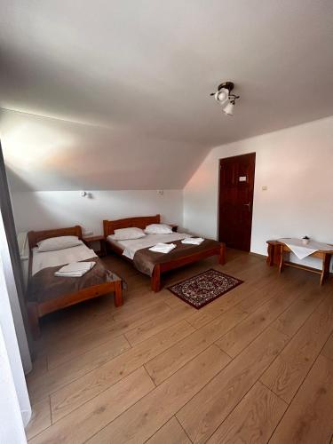 a room with two beds and a wooden floor at PENSIUNEA KELEMEN in Praid
