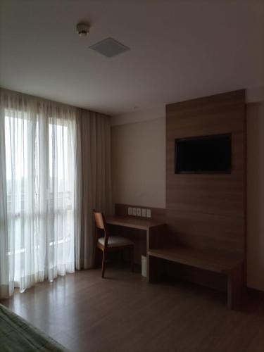 Zimmer mit einem Schreibtisch und einem TV in der Unterkunft Condomínio Vista Azul Hotel in Pedra Azul