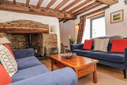 a living room with two blue couches and a fireplace at Court Cottage - cosy traditional cottage near lovely beaches in Kingsbridge