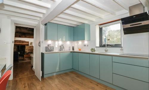 een keuken met blauwe kasten en een raam bij Court Cottage - cosy traditional cottage near lovely beaches in Kingsbridge