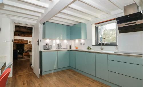 a kitchen with blue cabinets and a window at Court Cottage - cosy traditional cottage near lovely beaches in Kingsbridge