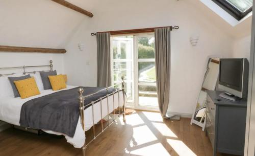 een slaapkamer met een bed, een tv en een raam bij Court Cottage - cosy traditional cottage near lovely beaches in Kingsbridge