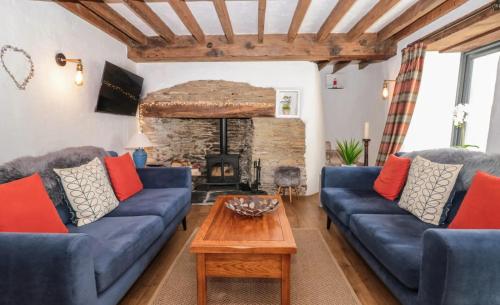 a living room with blue couches and a fireplace at Court Cottage - cosy traditional cottage near lovely beaches in Kingsbridge