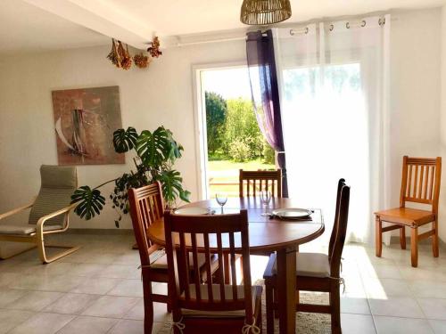 une salle à manger avec une table et des chaises et une fenêtre dans l'établissement L’Eucalyptus Blanc, claire, paisible,fonctionnelle, à Plouhinec