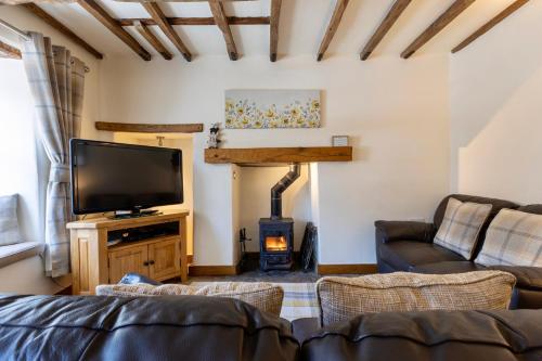 a living room with a tv and a fireplace at Character Cottage In West Burton, Wensleydale in West Burton