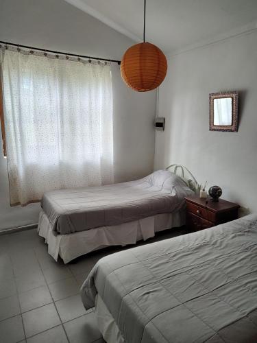 a bedroom with two beds and a window and a lamp at SAN ANTONIO de Arredondo la casa de Andrea in San Antonio de Arredondo