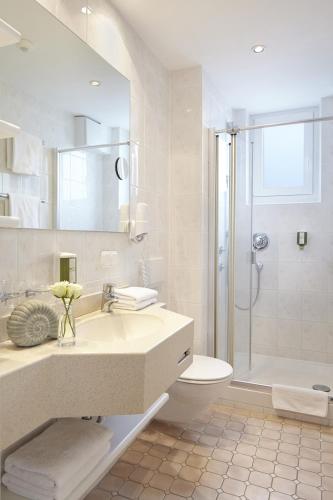 a bathroom with a sink and a toilet and a shower at Hotel Ancora Timmendorfer Strand, Pool inklusive in Timmendorfer Strand