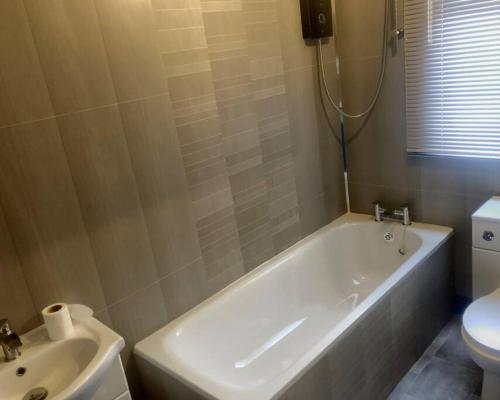 a bathroom with a tub and a toilet and a sink at Stainsby House 4 Bedrooms Workstays UK in Stockton-on-Tees