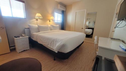 a hotel room with a large bed with white sheets at Hôtel Aquamer in Carleton sur Mer