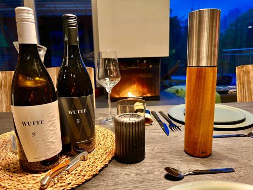 two bottles of wine sitting on a table with glasses at Ferienhaus auf 7 ha Alleinlage - Pool,Whirlpool, Sauna - Das Refugium Südsteiermark in Lieschen