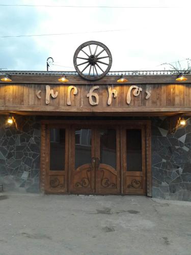 a building with a sign on it with a wheel on top at Xrchit (Խրճիթ) in Gyumri