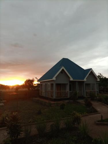 a house with a blue roof and a sunset at Kili View Lodge in Moshi