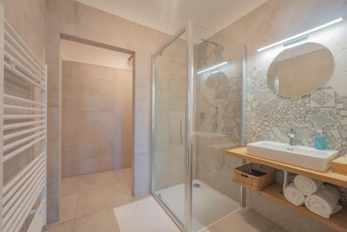 La salle de bains est pourvue d'une douche, d'un lavabo et d'un miroir. dans l'établissement Vlaštovčí dům, à Nové Město nad Metují