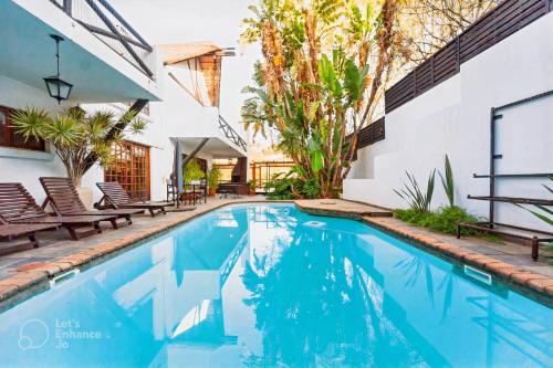 a swimming pool in front of a house with chairs at PRETORIA MANSION Boutique Hotel in Pretoria