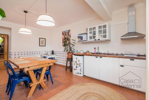 uma grande cozinha com uma mesa de madeira e cadeiras azuis em Casa Zeferina - Zeferina Family em Leiria