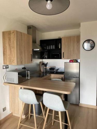 une cuisine avec une table en bois et deux chaises blanches dans l'établissement Appartement de 25 m² à Blonville, à Blonville-sur-Mer