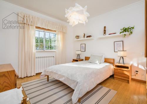 ein weißes Schlafzimmer mit einem Bett und einem Fenster in der Unterkunft Casa Zeferina - Zeferina Family in Leiria