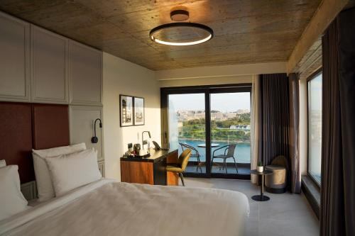 a bedroom with a bed and a desk and a balcony at The Londoner Hotel Sliema in Sliema