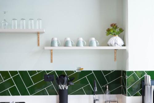 a kitchen with green and white tile on the wall at Royal Living Poblado in Medellín