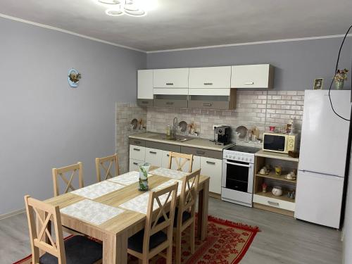 uma cozinha com uma mesa de madeira e um frigorífico branco em Anikó kulcsosház em Corund