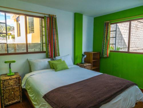 um quarto verde com uma cama e 2 janelas em HOSTAL Casa Verde em Otavalo